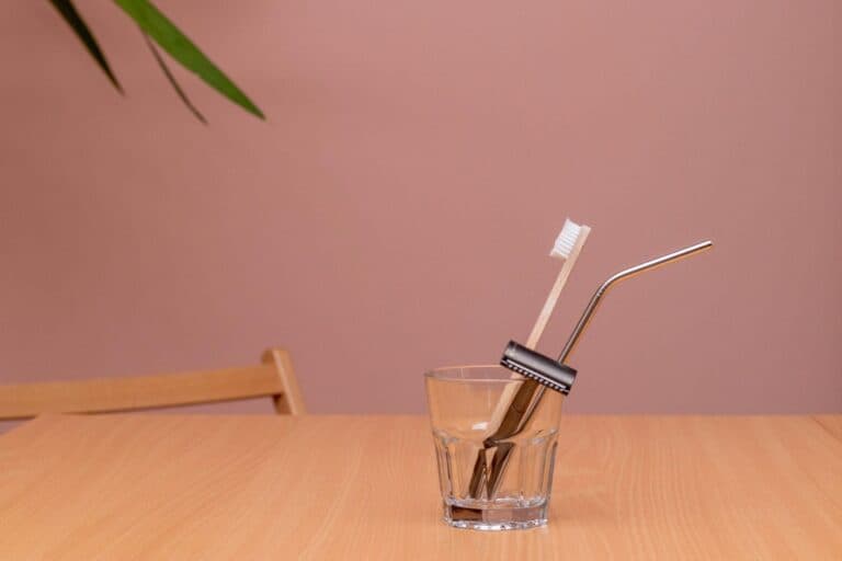 Zero waste swaps: bamboo toothbrush, metal straw and safety razor in a glass