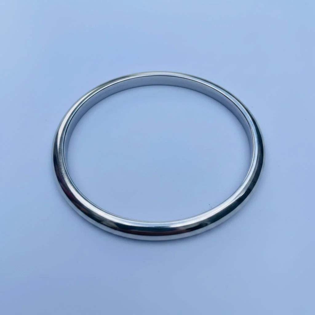 A polished silver metal circular bracelet or bangle, photographed from above on a light blue background.