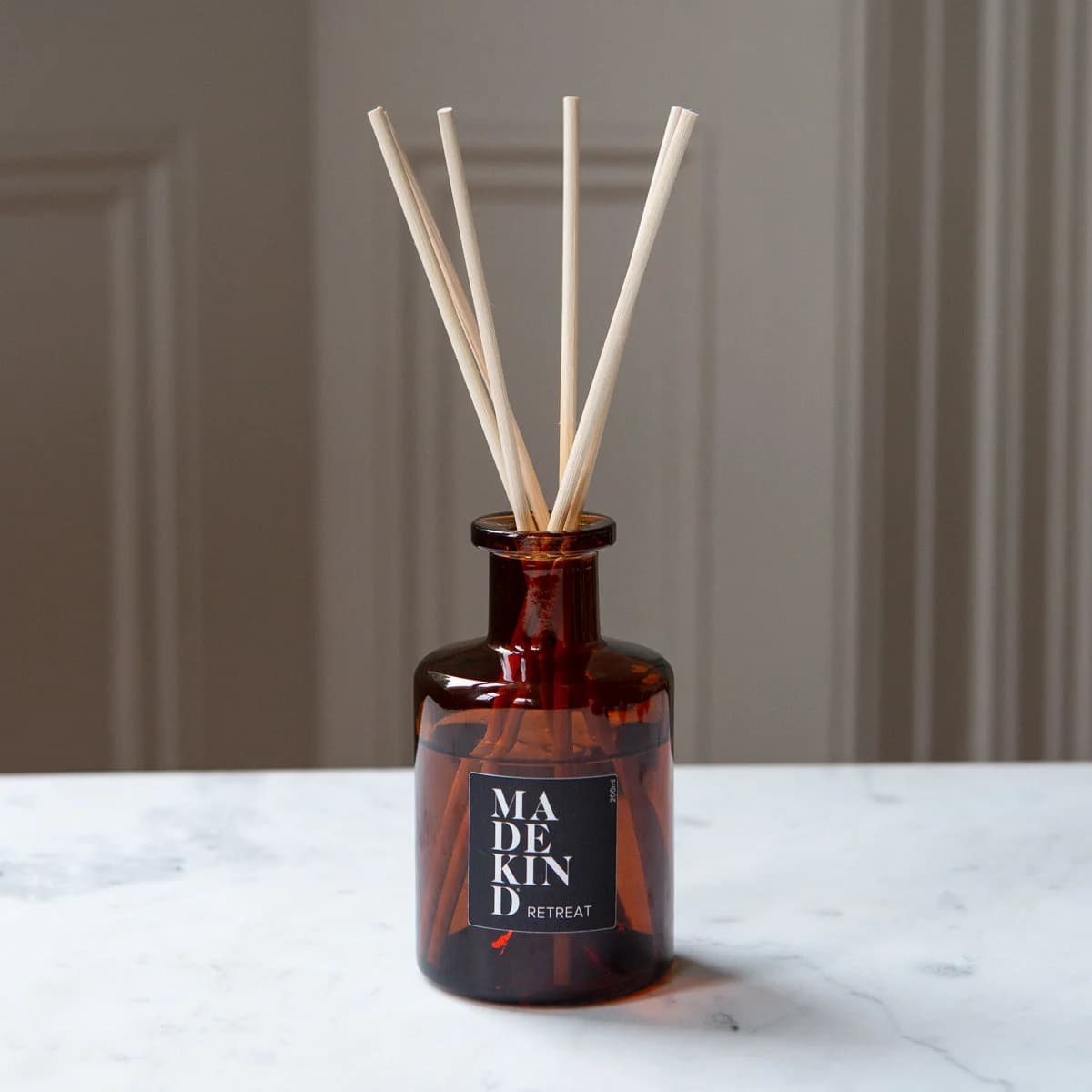 Amber glass apothecary reed diffuser bottle with natural reeds on a marble table