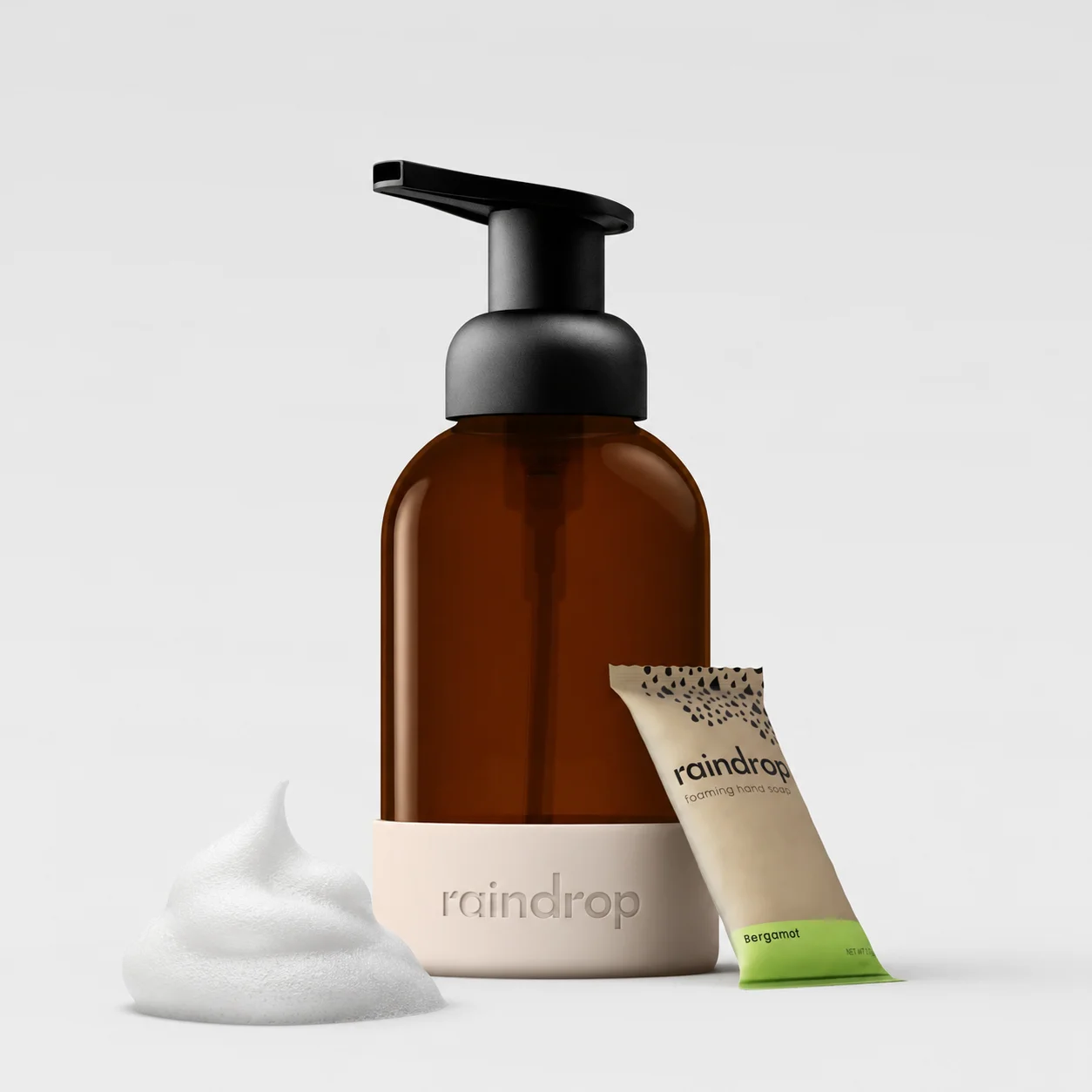 Brown bottle with black pump, white cap, and small brown packet labeled 'raindrop' on a light gray background.